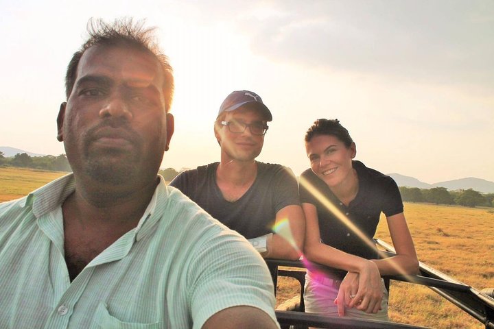 Two guests and their tour host outdoors at sunset