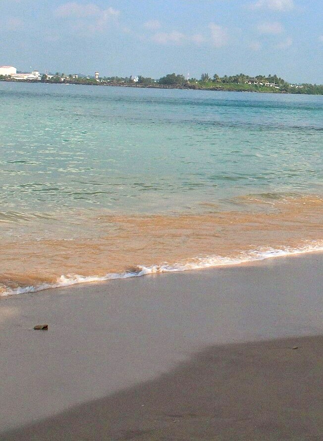 Empty shoreline and gentle waves at Jungle Beach, Unawatuna