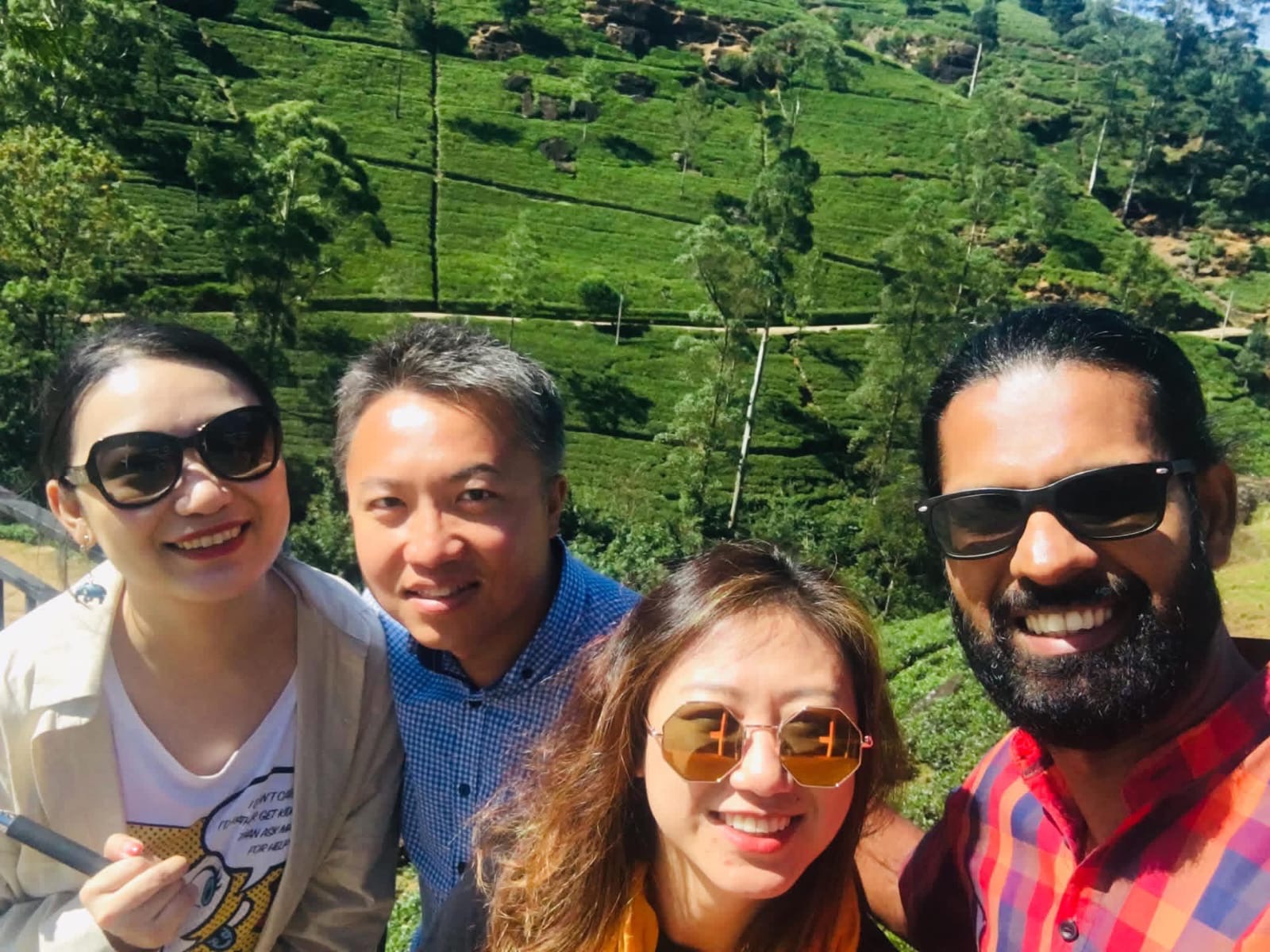 A group selfie of guests and their tour host among the tea country hills