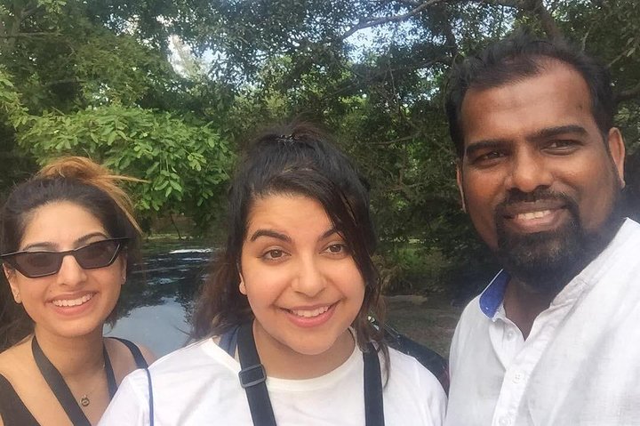 Two guests and their tour host beside a tree-lined waterway