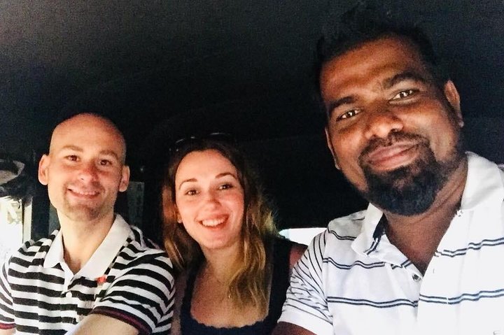 Two guests and their tour host taking a selfie inside a vehicle